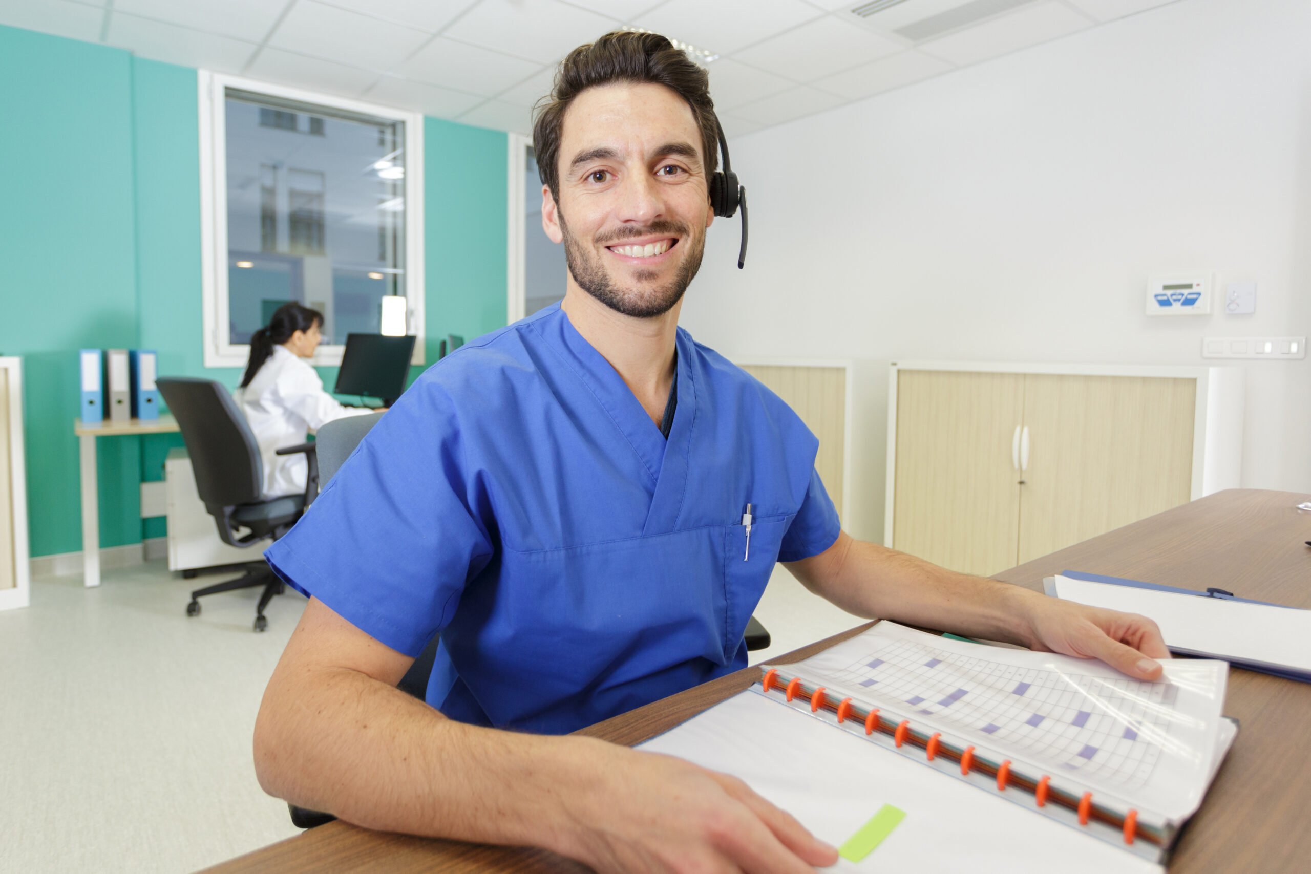 adobestock_317358164-scaled-1 Male administrative professional in scrubs with calendar